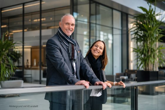 Volker Loibl und Melanie Reuß von apollo consulting an einem Glasgeländer in der Bürolobby