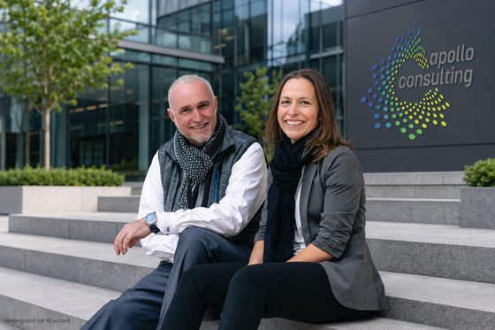 Volker Loibl und Melanie Reuß von apollo consulting auf den Stufen vor dem Firmenschild
